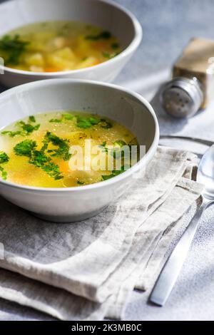 Chicken soup with vegetables served in the bowls on white concrete table ready for dinner Stock Photo