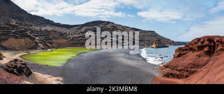 Rough rock formations surrounding pool with clean water on shore of sea against cloudy blue sky in Charcos de los Clicos in Lanzarote, Spain Stock Photo