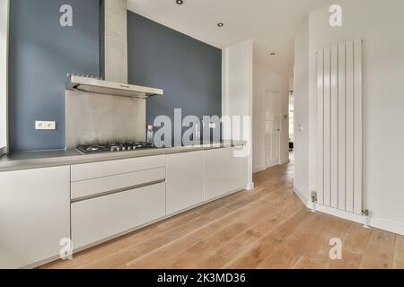 White counters with sink and appliances located against wall with built in furniture in light kitchen at home Stock Photo