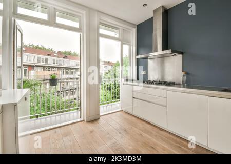 White counters with sink and appliances located against wall with built in furniture in light kitchen at home Stock Photo