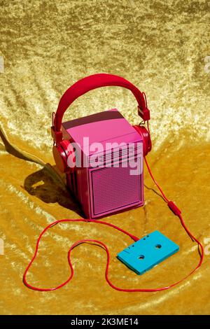 From above of vintage pink stereo speaker in headset connected to audio tape placed on yellow textile in studio Stock Photo