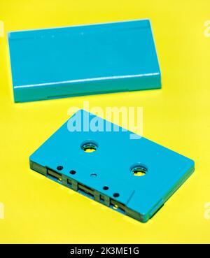 High angle of isolated vintage blue audio cassette and case placed on yellow background in studio Stock Photo