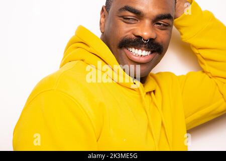 Happy bearded man in yellow hoodie smiling and looking at camera against white background Stock Photo