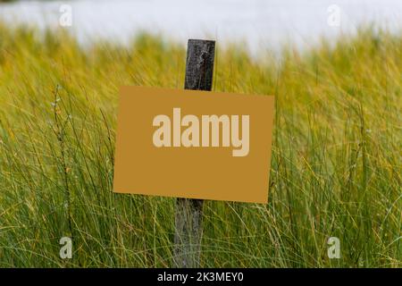Blank yellow sign on a wooden pole among the green grass Stock Photo