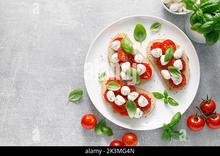 Caprese toasts with mini mozzarella cheese, cherry tomato and basil, top view Stock Photo