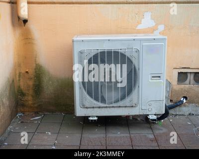 Old air conditioner on the corner of the house. Air conditioning among on the wall in a dirty street. Technique for climate control. Urban environment Stock Photo
