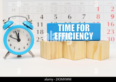 Time concept. Against the background of the calendar is an alarm clock, cubes and a blue block with the inscription - Time for Efficiency Stock Photo