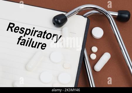 Medical concept. On a brown surface lies a stethoscope, pills and a notepad with the inscription - Respiratory failure Stock Photo