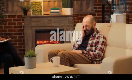 Displeased man complaining about conflict with wife at couple therapy session, talking to psychologist in office. Attending psychotherapy appointment with counselor, receiving advice. Stock Photo