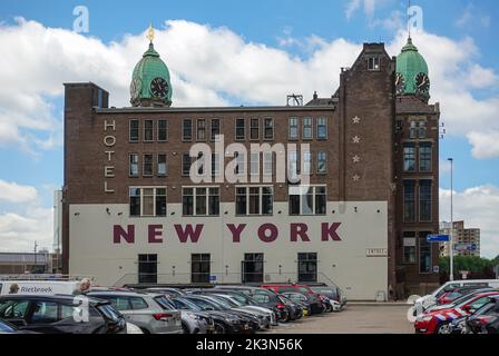 Rotterdam, Netherlands - July 11, 2022: Back side of brown stone historic New York hotel with 2 green dome towers under blue sky on Kop van Zuid dock Stock Photo