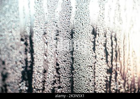 Texture of misted glass in winter. Frozen drops of water in sun on window. Dawn outside window. Abstract background. Selective focus. Stock Photo