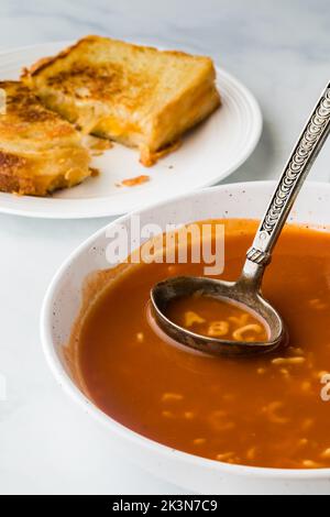 A bowl of alphabet tomato soup with the letters A, B, C in the ladle. Stock Photo