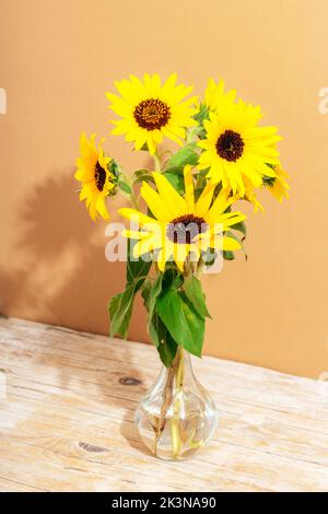 Bouquet of sunflowers in glass vase on wooden table. Closeup. Stock Photo