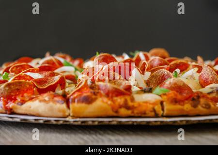 Side-view of thin crust Columbus-style pepperoni vegetable pizza Stock Photo