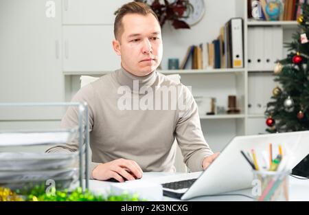 Man working in Christmas decorated office Stock Photo