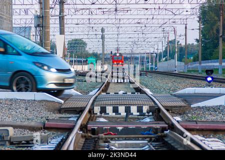 Kemerovo, Russia - September 01, 2022. Minibus getting ready to cross a railway crossing in front of an approaching train violating traffic rules, sel Stock Photo