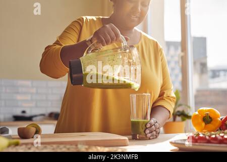 Sunlit shot of smiling black woman enjoying healthy smoothie at home kitchen, copy space Stock Photo