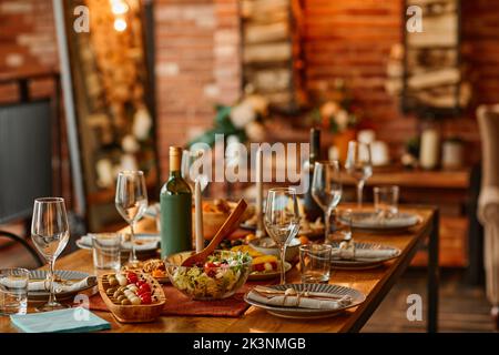 Warm toned background image of wooden dinner table set with dishes for cozy cabin party Stock Photo
