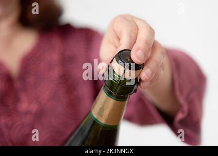 Unrecognizable woman opening a bottle of champagne or cider. Concept of festivity and celebration. Close up image with copy space. Stock Photo