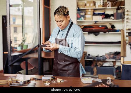 Waist up portrait of modern artisan working with leather in shop, copy space Stock Photo