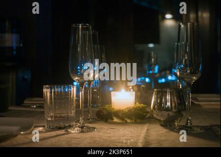 a candle and a bunch of empty wineglasses on the table, night scene Stock Photo