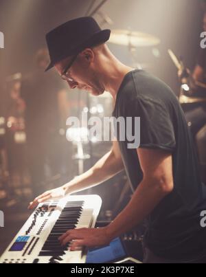 He has the world of music at his fingertips. A young man playing a keyboard on stage at a music concert. Stock Photo