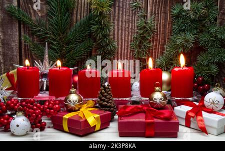 Red Christmas candles and Christmas gift boxes against wooden background Stock Photo