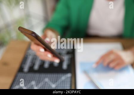 Businesswoman hand holding mobile phone using mobile business app and financial charts closeup Stock Photo