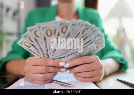 Business office desk woman counting money on hands analyzing income charts and graphs Stock Photo