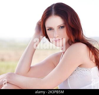 Beauty that takes the breath away. A young redheaded woman sitting outside. Stock Photo