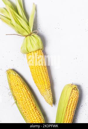 Top view of raw organic super sweet corns with corn silk and skin on white background. Stock Photo