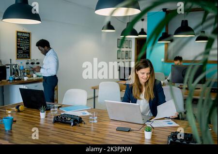 Focused diverse colleagues working on laptop and computer in modern coworking space Stock Photo