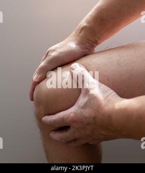 A person with knee pain massaging it for relief. Injuries. Arthritis. Stock Photo