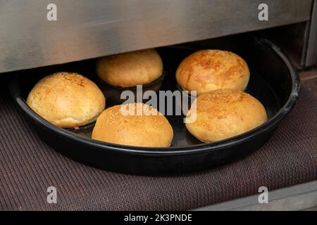 Freshly baked hot burger buns in an industrial oven Stock Photo