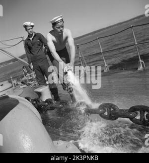 During World war II. The war ship Sverige during navy exercises at sea. The anchor chain is being pulled up and a sailor is hosing it with water to remove clay and mud from it.  Sweden june 1940. Kristoffersson ref 141 Stock Photo