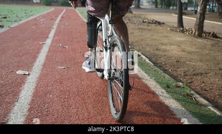 A disabled amputee cyclist riding bicycle with prosthetic leg Stock Photo
