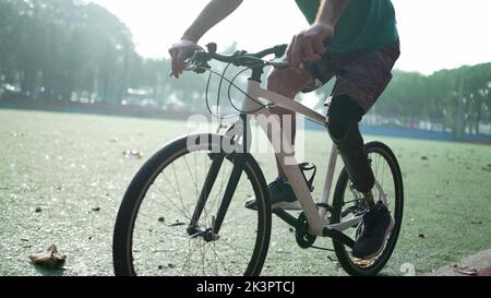 A disabled amputee cyclist riding bicycle with prosthetic leg Stock Photo