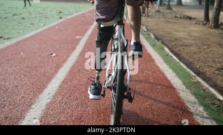 A disabled amputee cyclist riding bicycle with prosthetic leg Stock Photo