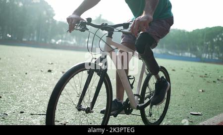 A disabled amputee cyclist riding bicycle with prosthetic leg Stock Photo