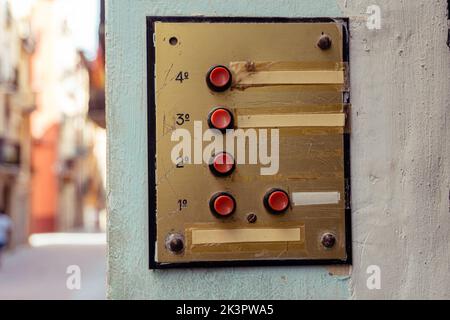 An old elevator panel with red buttons on a wall outdoors in daylight Stock Photo