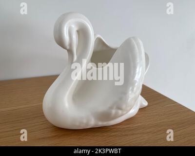 A ceramic ashtray in the form of a white swan on a wooden table Stock Photo