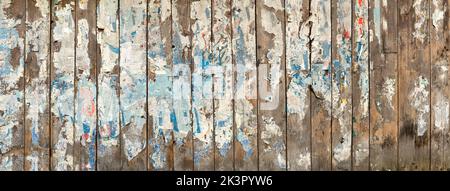 Weathered remains of old vintage advertising posters on a wooden wall Stock Photo