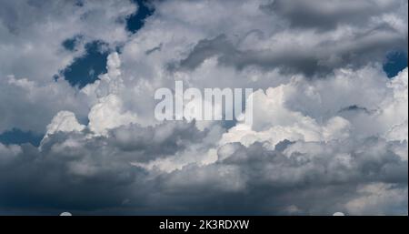 Big bright clouds against dark blue sky, cloud in dramatic light, panoramic view Stock Photo