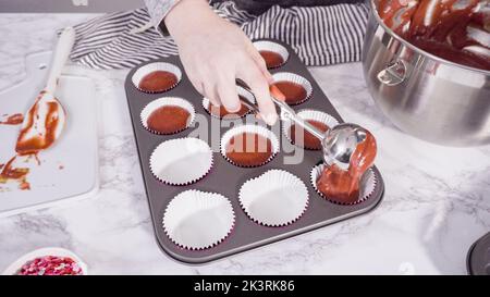 Scooping cupcake batter with a dough scoop into cupcake foil liners to bake  gingerbread cupcakes Stock Photo - Alamy