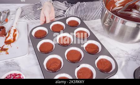 Scooping cupcake batter with a dough scoop into cupcake foil