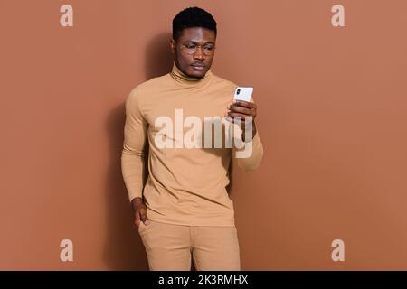 Portrait of attractive focused guy using device gadget writing web surfing isolated over brown color background Stock Photo