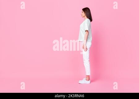 Full size side profile photo of gorgeous serious girl bob hairstyle striped t-shirt look empty space isolated on pink color background Stock Photo