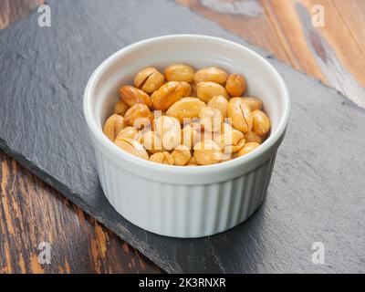 peanuts fried with salt in a small bowl on a black stone Board Stock Photo