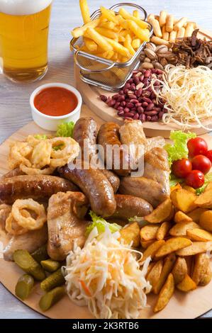 tasty assorted beer snacks: chicken wings, grilled sausages, potatoes, nuts cheese croutons Stock Photo