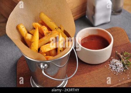 tasty French fries in a metal bucket with tomato sauce Stock Photo